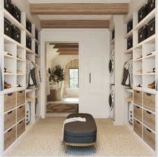 Primary Closet featuring stacked washer / drying machine and light colored carpet