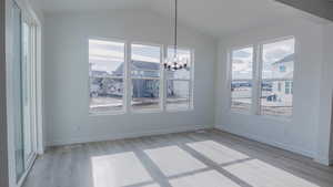 Unfurnished dining area with vaulted ceiling, a healthy amount of sunlight, and a notable chandelier