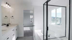 Full bath with double vanity, baseboards, a bath, tile patterned flooring, and a sink