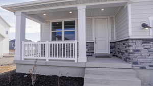 View of exterior entry featuring stone siding and covered porch