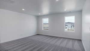 Spare room with carpet, a textured ceiling, and baseboards