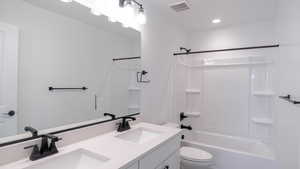 Bathroom featuring toilet, shower / bathing tub combination, a sink, and visible vents