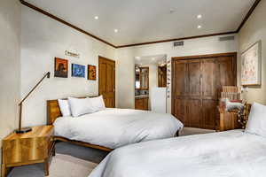 Bedroom featuring ornamental molding, carpet floors, and ensuite bath