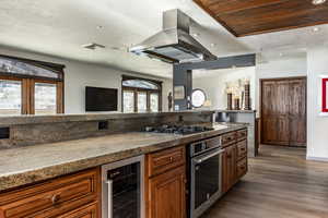 Kitchen with island range hood, wood-type flooring, beverage cooler, and appliances with stainless steel finishes