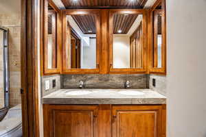 Bathroom featuring vanity, backsplash, a shower with door, and toilet