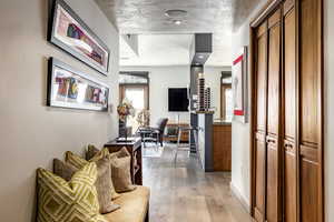 Corridor with a textured ceiling and light wood-type flooring