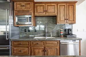 Kitchen featuring appliances with stainless steel finishes, sink, and backsplash