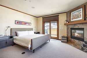 Carpeted bedroom with access to exterior, crown molding, and a fireplace