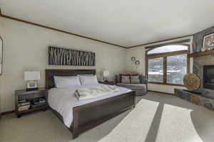 Carpeted bedroom with crown molding and a stone fireplace