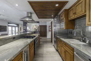 Kitchen featuring island exhaust hood, light stone countertops, sink, and beverage cooler