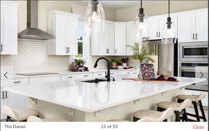 Kitchen with sink, wall chimney range hood, a kitchen breakfast bar, stainless steel appliances, and white cabinets