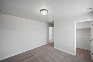 Unfurnished bedroom featuring a walk in closet, a closet, and carpet