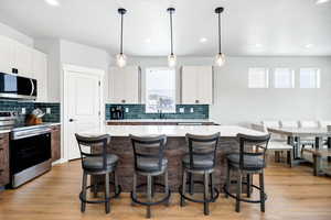 Kitchen featuring a kitchen island, appliances with stainless steel finishes, and decorative light fixtures