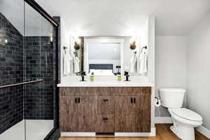 Bathroom featuring toilet, an enclosed shower, wood-type flooring, a textured ceiling, and vanity