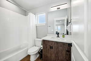 Full bathroom with vanity, wood-type flooring, toilet, and shower / bathtub combination with curtain