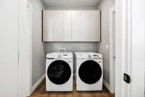 Washroom with cabinets, dark hardwood / wood-style flooring, and separate washer and dryer