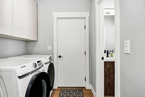 Washroom with cabinets, washer and clothes dryer, and light hardwood / wood-style floors