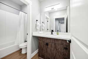 Full bathroom featuring shower / tub combo with curtain, vanity, toilet, and hardwood / wood-style floors