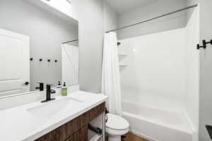 Full bathroom with shower / bathtub combination with curtain, vanity, and toilet