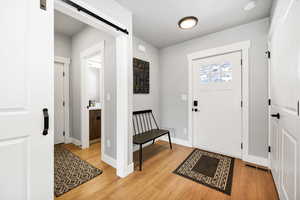 Entrance foyer with a barn door and light hardwood / wood-style flooring