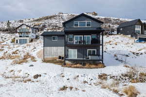 Snow covered rear of property with a balcony and a mountain view