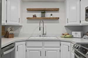 Kitchen with white cabinetry, appliances with stainless steel finishes, and sink