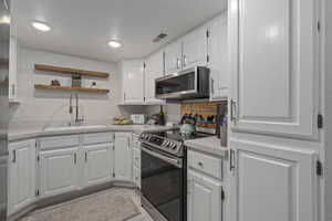 Kitchen featuring white cabinetry, appliances with stainless steel finishes, sink, and light tile patterned floors