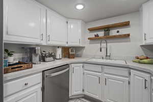 Kitchen featuring sink, stainless steel dishwasher, and white cabinets