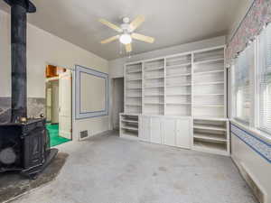 Living room with carpet floors, ceiling fan, and a wood stove