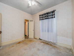 Carpeted empty room with ceiling fan and a textured ceiling