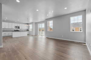 Unfurnished living room featuring a notable chandelier, a textured ceiling, and light wood-type flooring