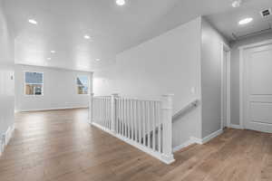 Hallway featuring a textured ceiling and light wood-type flooring