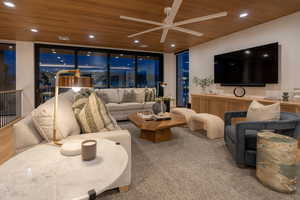 Living room featuring ceiling fan, floor to ceiling windows, and wooden ceiling