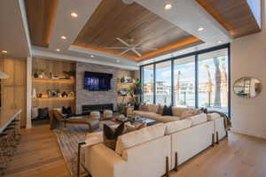 Living room featuring wooden ceiling, built in features, light hardwood / wood-style floors, and a tray ceiling