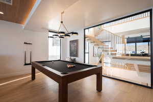 Rec room featuring hardwood / wood-style flooring, pool table, a mountain view, and an inviting chandelier