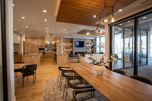 Dining space featuring a fireplace, sink, wood ceiling, floor to ceiling windows, and light hardwood / wood-style flooring