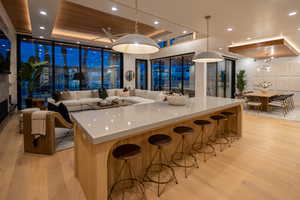 Kitchen with pendant lighting, a tray ceiling, a spacious island, and light wood-type flooring