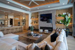 Living room with wood ceiling, a raised ceiling, light hardwood / wood-style floors, and a brick fireplace