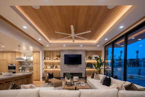 Living room featuring wood ceiling, a raised ceiling, a brick fireplace, and light hardwood / wood-style flooring