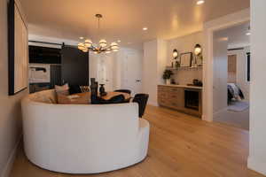 Living room with a barn door, a chandelier, and light hardwood / wood-style flooring