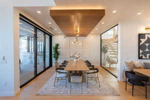 Dining space with a wall of windows, a chandelier, and light hardwood / wood-style floors