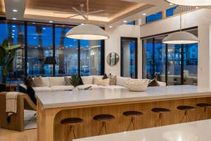 Interior space featuring expansive windows, hanging light fixtures, a tray ceiling, wooden ceiling, and light wood-type flooring