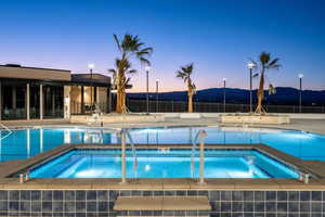 Pool at dusk featuring a mountain view and a community hot tub