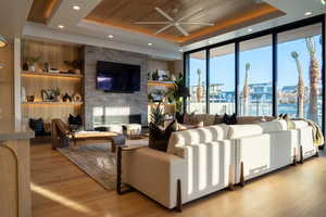 Living room featuring a brick fireplace, light wood-type flooring, wood ceiling, and a tray ceiling