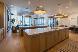 Kitchen with a spacious island, decorative light fixtures, light hardwood / wood-style floors, and sink