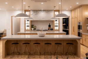 Kitchen with decorative light fixtures, light brown cabinetry, a kitchen bar, and a spacious island