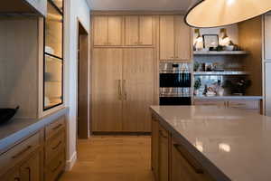 Kitchen with light brown cabinetry, light hardwood / wood-style floors, and stainless steel double oven