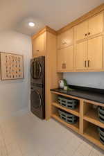 Laundry area featuring cabinets and stacked washing maching and dryer