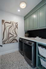 Clothes washing area featuring cabinets and separate washer and dryer