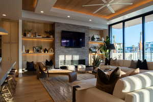 Living room featuring a brick fireplace, wooden ceiling, a raised ceiling, and light wood-type flooring